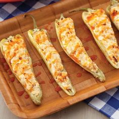 four cheesy stuffed peppers on a wooden tray