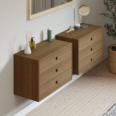 two wooden dressers sitting next to each other near a mirror and potted plant