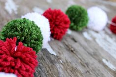 red and green pom - poms sitting on top of a wooden table next to each other