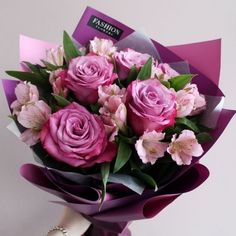 a bouquet of pink roses wrapped in purple paper