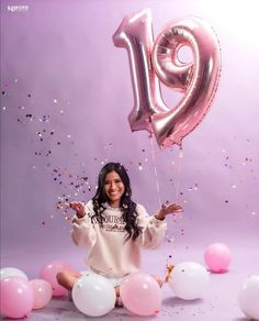 a woman sitting on the ground with balloons and confetti in front of her