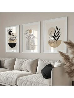 three framed art prints hanging on the wall above a white couch in a living room