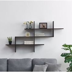 three shelves on the wall above a couch with books and vases sitting on it