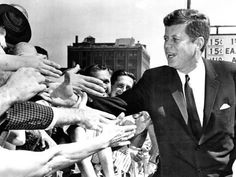 a man in a suit and tie is surrounded by people holding his hands out to him