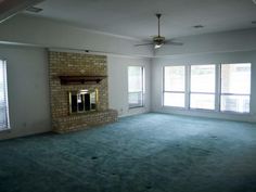 an empty living room with large windows and a fireplace