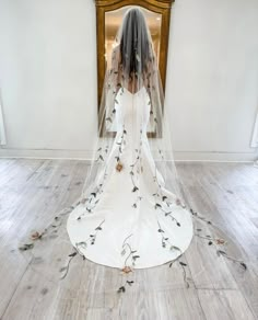 a woman in a wedding dress with a veil over her head and flowers on it