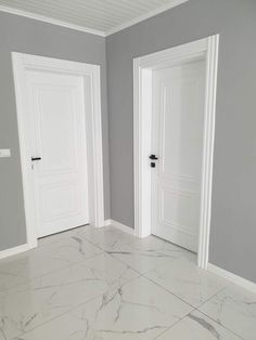 an empty room with two white doors and gray walls in the corner is seen here