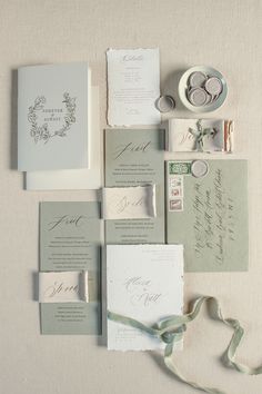 the wedding stationery is laid out on top of each other with ribbons and rings