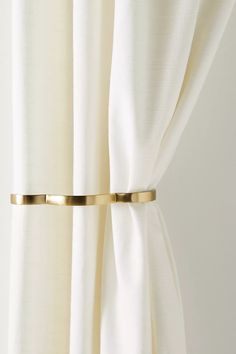 the curtain is closed and has gold metal bar on it's side, with white drapes in the background