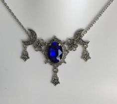 This is a new handmade necklace. It is made with antiqued silver plated filigrees, accented with a high quality DARK BLUE glass rhinestone. Decorated portion is 2 1/2" wide and 1 3/4" tall in the center. Necklace is adjustable 15-18" with a lobster clasp and chain extender. If you would like a different length, please send us a message. Deep Blue Necklace, Blue Gothic Metal Necklace, Handmade Gothic Blue Necklace, Handmade Blue Gothic Necklace, Gothic Blue Metal Jewelry, Blue Gothic Metal Jewelry, Gothic Blue Jewelry For Gifts, Blue Gothic Jewelry For Gifts, Blue Gothic Jewelry For Gift