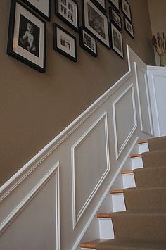 a staircase with pictures on the wall above it and framed photos hanging on the wall