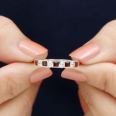 a woman's hand holding a ring with three stones on the middle of it