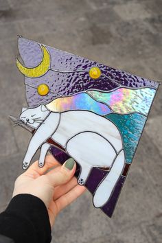 a hand holding up a stained glass piece with an animal on it's back