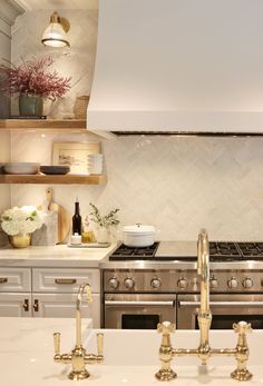 a kitchen with white counter tops and gold faucets on the stove top next to an oven