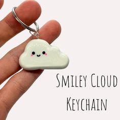 a hand holding a keychain with a small white cloud on it's face