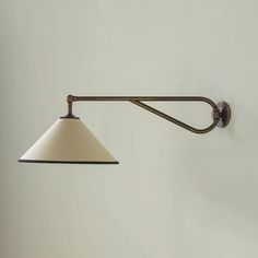 a wall light with a white shade hanging from it's side on the wall