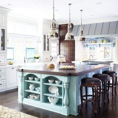 a large kitchen with an island in the middle and two stools at the end