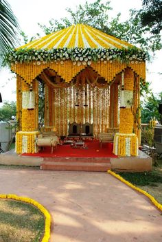 a yellow and white gazebo decorated with flowers