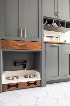 a kitchen with gray cabinets and white counter tops, two bowls on the bottom shelf