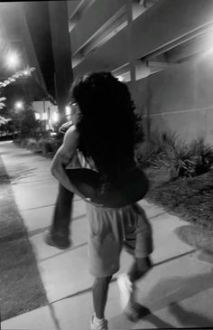 a woman walking down a sidewalk at night with a frisbee in her hand