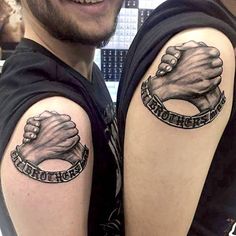 two men with tattoos on their arms holding hands