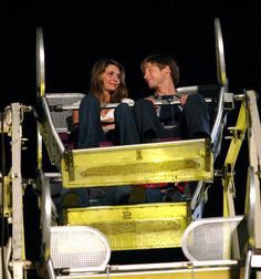 a man and woman sitting on top of a ferris wheel