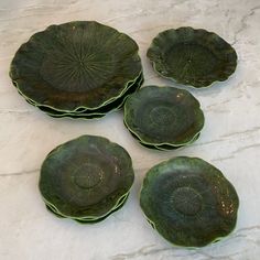 four green plates sitting on top of a white table