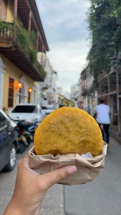 a person holding up a food item in their hand on the side of the road