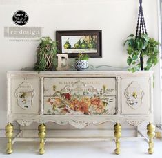 an old dresser with flowers painted on the side and gold handles is displayed in front of a white wall