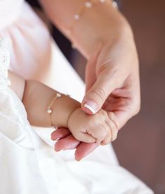 a close up of a person holding a small child's hand while wearing a wedding dress