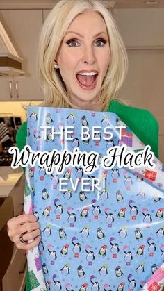 a woman holding up a blue wrapping paper with penguins on it and the words, the best wrapping hack ever