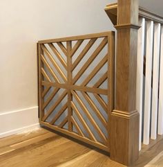 a wooden gate on top of a hard wood floor next to a banister and railing