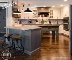 a kitchen with an island and two stools next to it on a hard wood floor