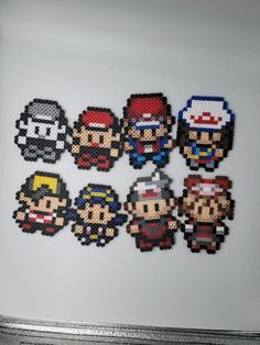 six pixelated video game characters are displayed on a white surface with silver trimmings