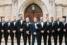 a group of men in tuxedos standing next to each other near a building