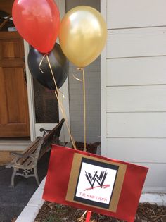 a sign with balloons attached to it in front of a house that is decorated for a wrestling event