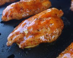 three pieces of chicken are being cooked on a grill