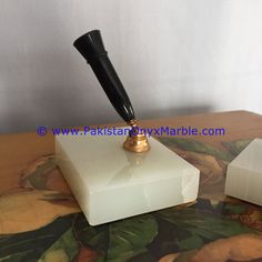 a pen sitting on top of a white block with a gold tip and black handle