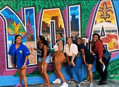 some girls are standing in front of a colorful wall