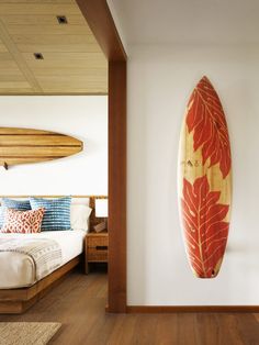 a surfboard mounted to the wall next to a bed in a room with wooden floors