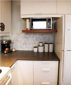 a kitchen with white cabinets and black counter tops is pictured in this image, there are three cups on the counter next to the microwave