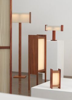 three wooden lamps sitting on top of white pedestals next to each other in a room