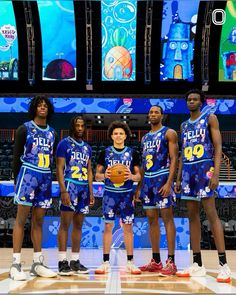 a group of young men standing on top of a basketball court holding a basketball ball