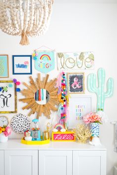 a white dresser topped with lots of pictures and art