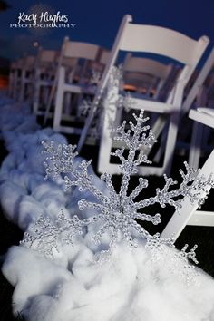 two white chairs sitting on top of snow covered ground next to each other in the grass