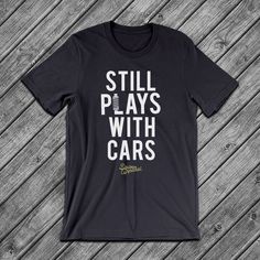 a black shirt that says still plays with cars