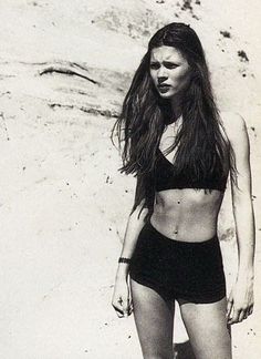 a black and white photo of a woman on the beach