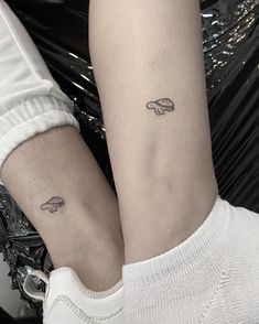 two people with matching tattoos on their legs, one is holding the other's leg