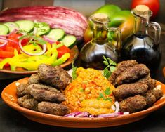 an assortment of meats and vegetables on a plate with condiments in the background