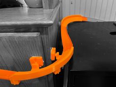 an orange plastic handle on a black cabinet